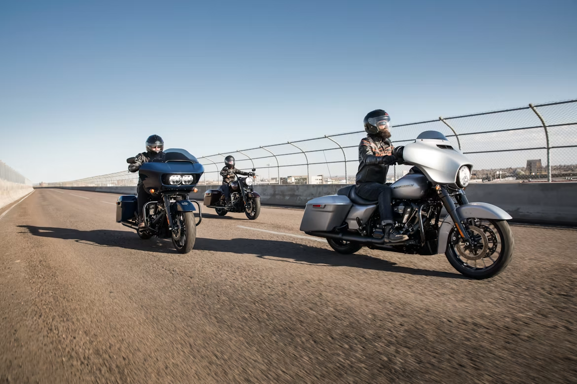 Trois Harley-Davidson roulant côte à côte sur une autoroute américaine.